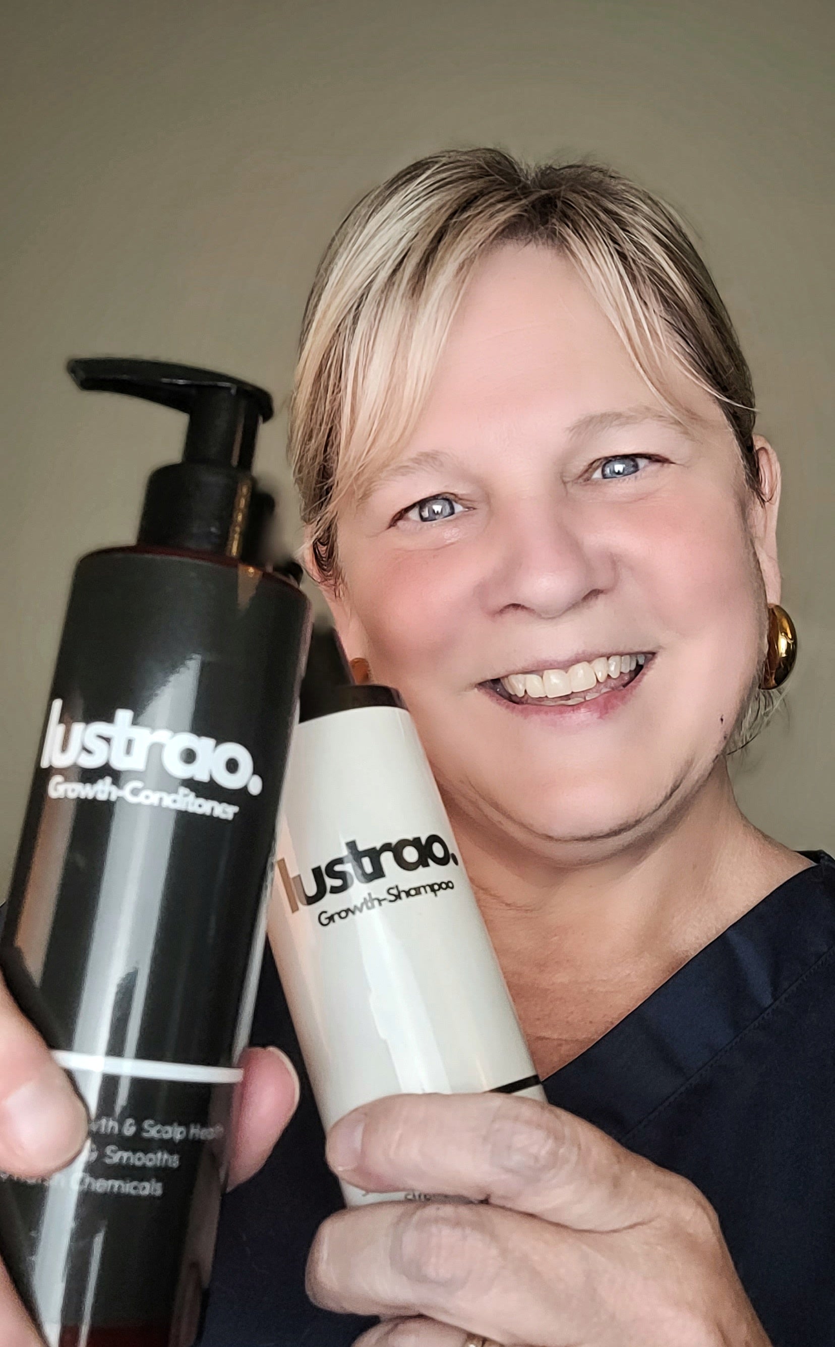 Woman holding two bottles of Lustrao hair care products against a plain background